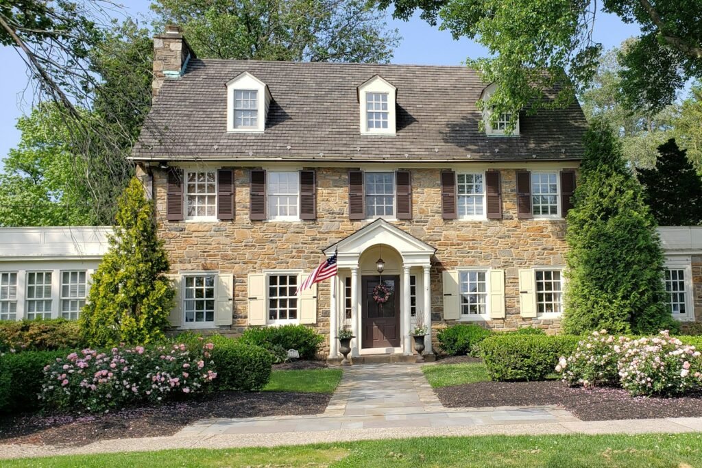 Classic stone and brick colonial home with a landscaped front yard